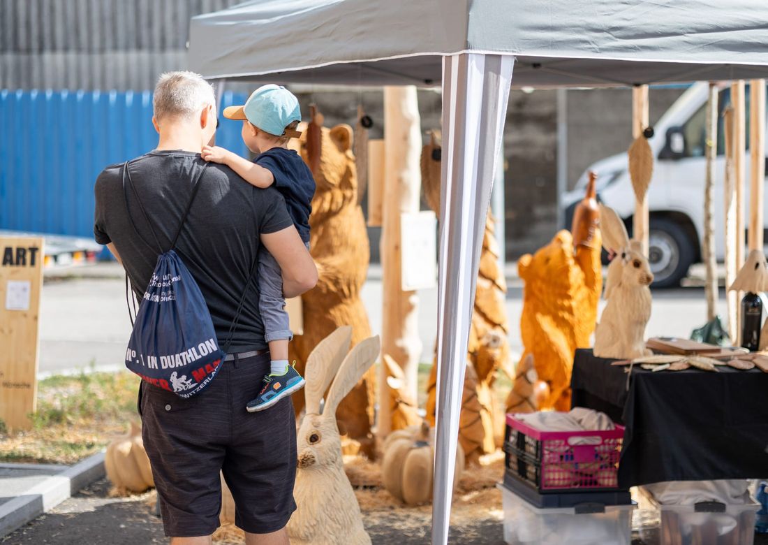 Ein Vater mit Kind schaut sich die Figuren am Stand an
