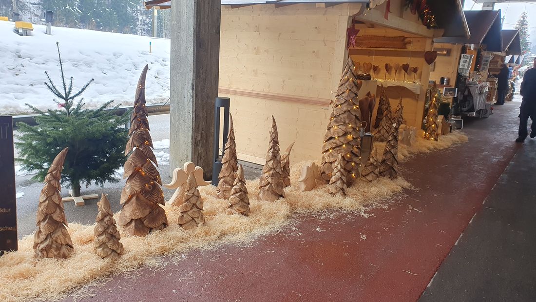 Geschnitzte Tannen vor den Ständen am Weihnachtsmarkt