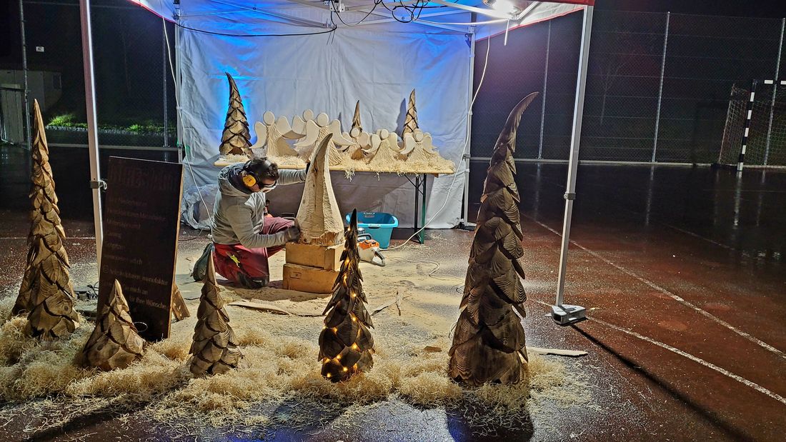 Beleuchteter Stand mit Tannen und Engeln am Weihnachtsmarkt