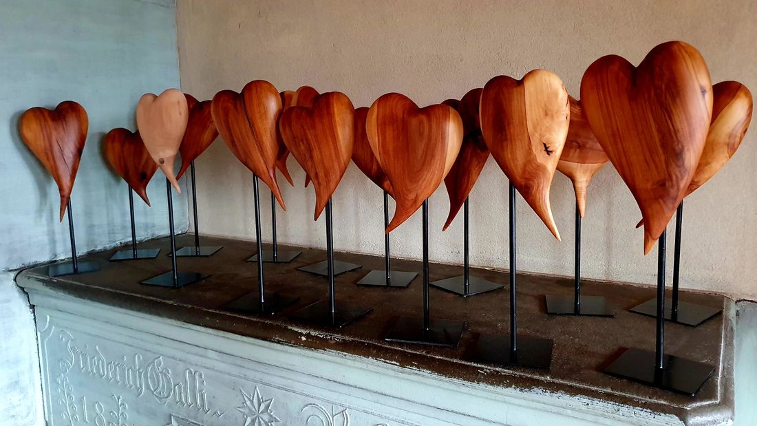 Viele Herzen aus Holz auf Ständern in einer Reihe