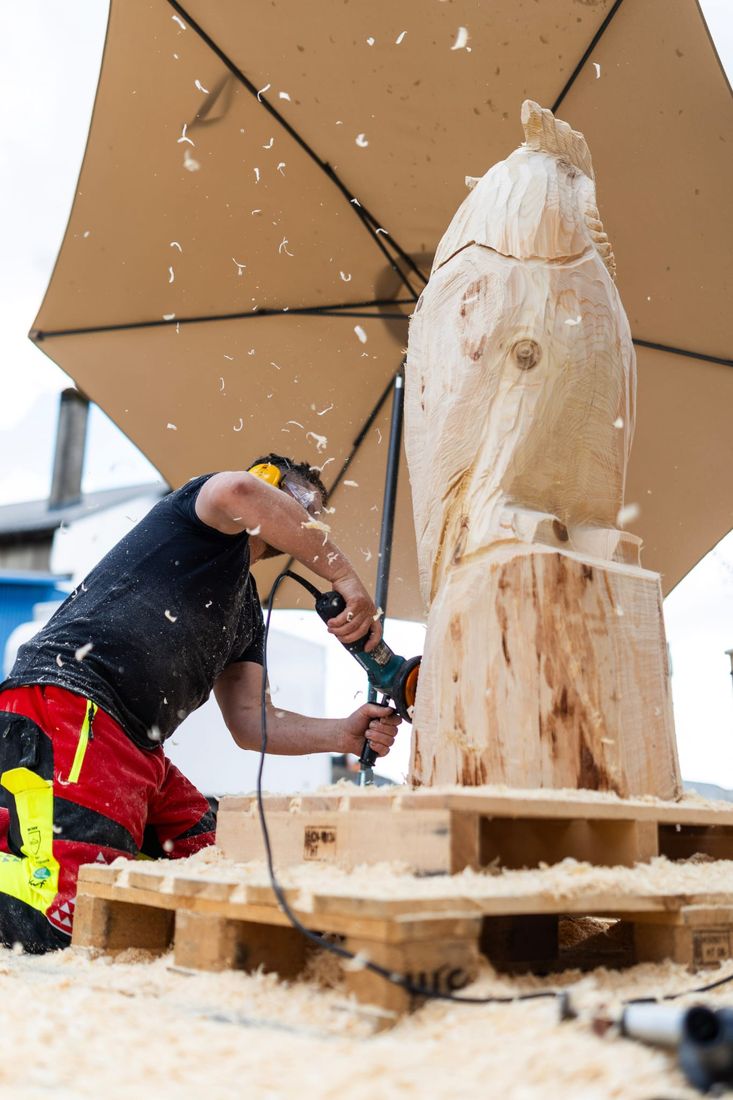 Jüre kniet unter dem Sonnenschirm und schleift an einer Figur