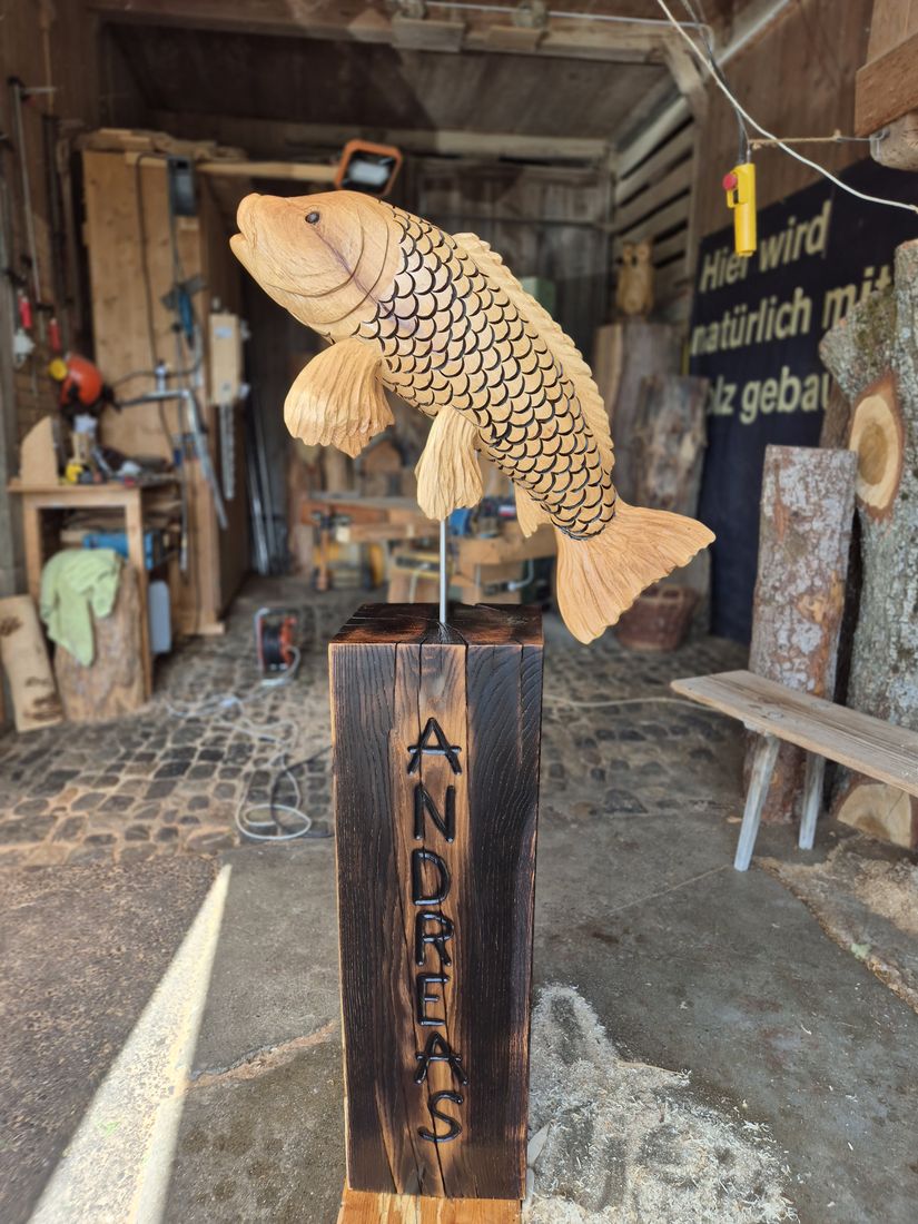 Fisch aus Holz auf einem Pfosten mit eingebranntem Namen